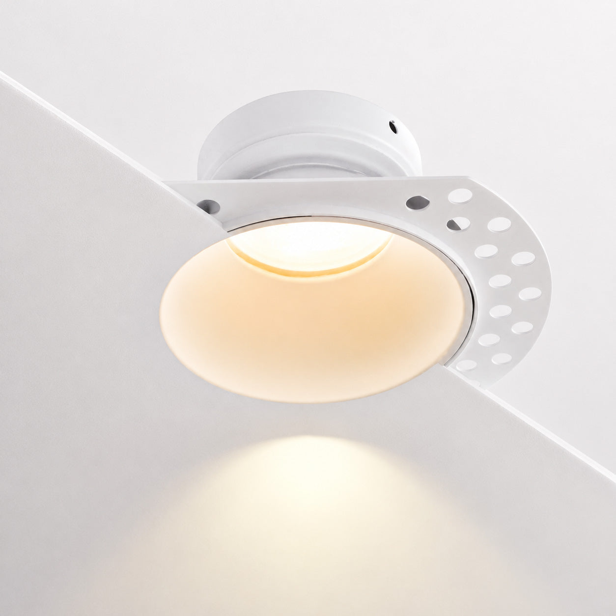 Trimless plaster-in downlight sitting flush in a smooth white ceiling