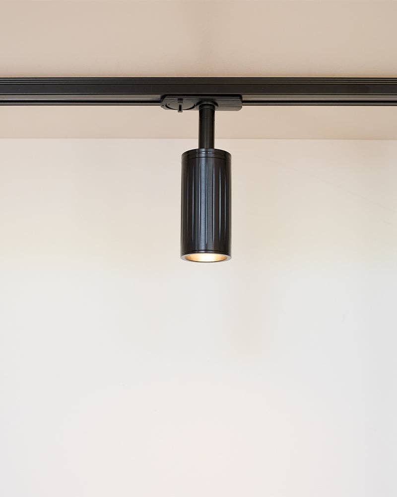 Luminar matt black ribbed spotlight on a black lighting track, lit
