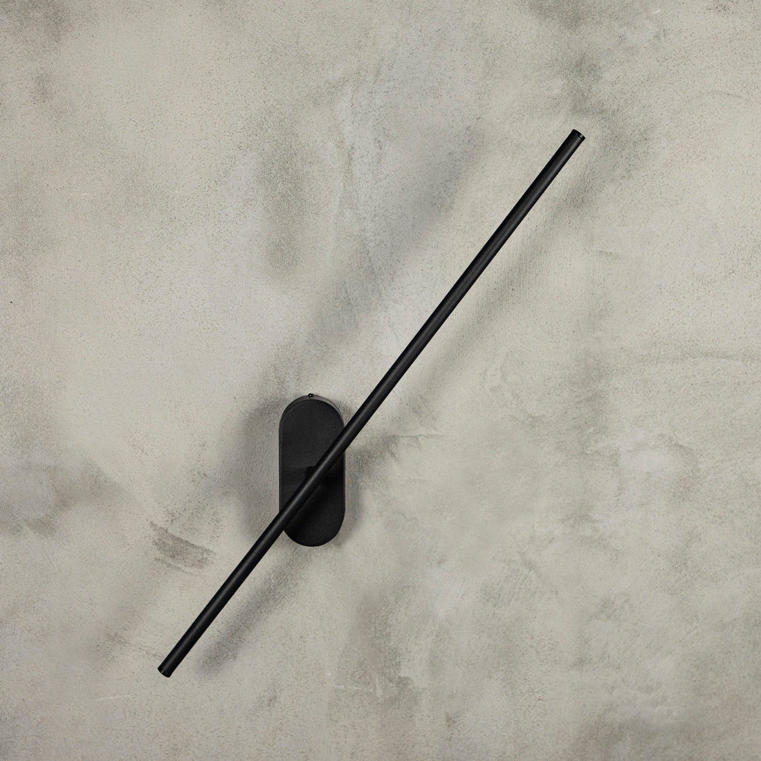Assos black wall light rotated to a diagonal on a limewashed wall