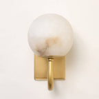 Satin brass alabaster wall light illuminated showing warm ambient glow