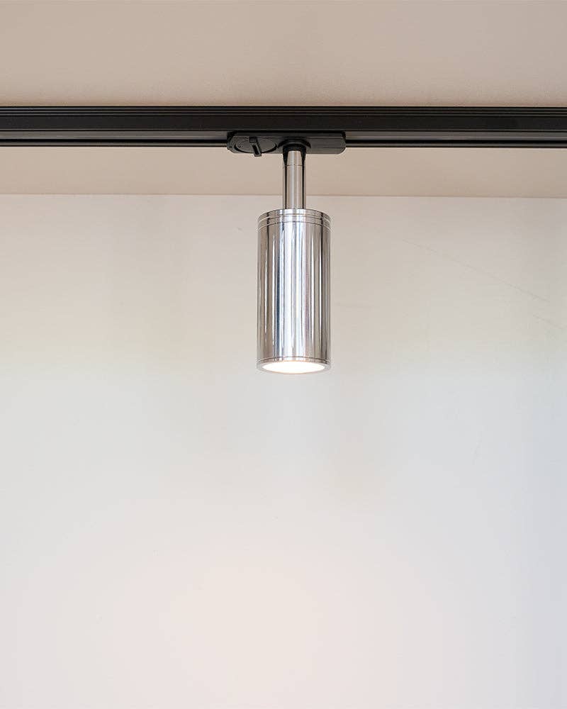 Luminar polished steel ribbed spotlight on a black lighting track, lit