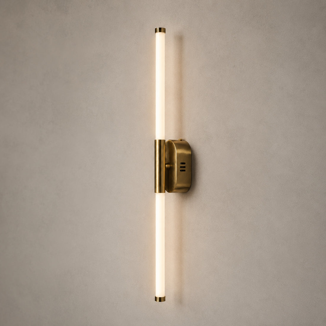 Akra 60cm twin-tube wall light glowing vertically on its brass bracket