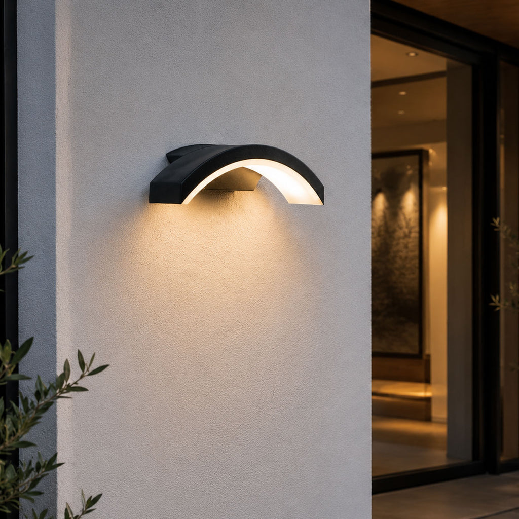 Arlen black arched LED wall light lit beside a modern front entrance at dusk