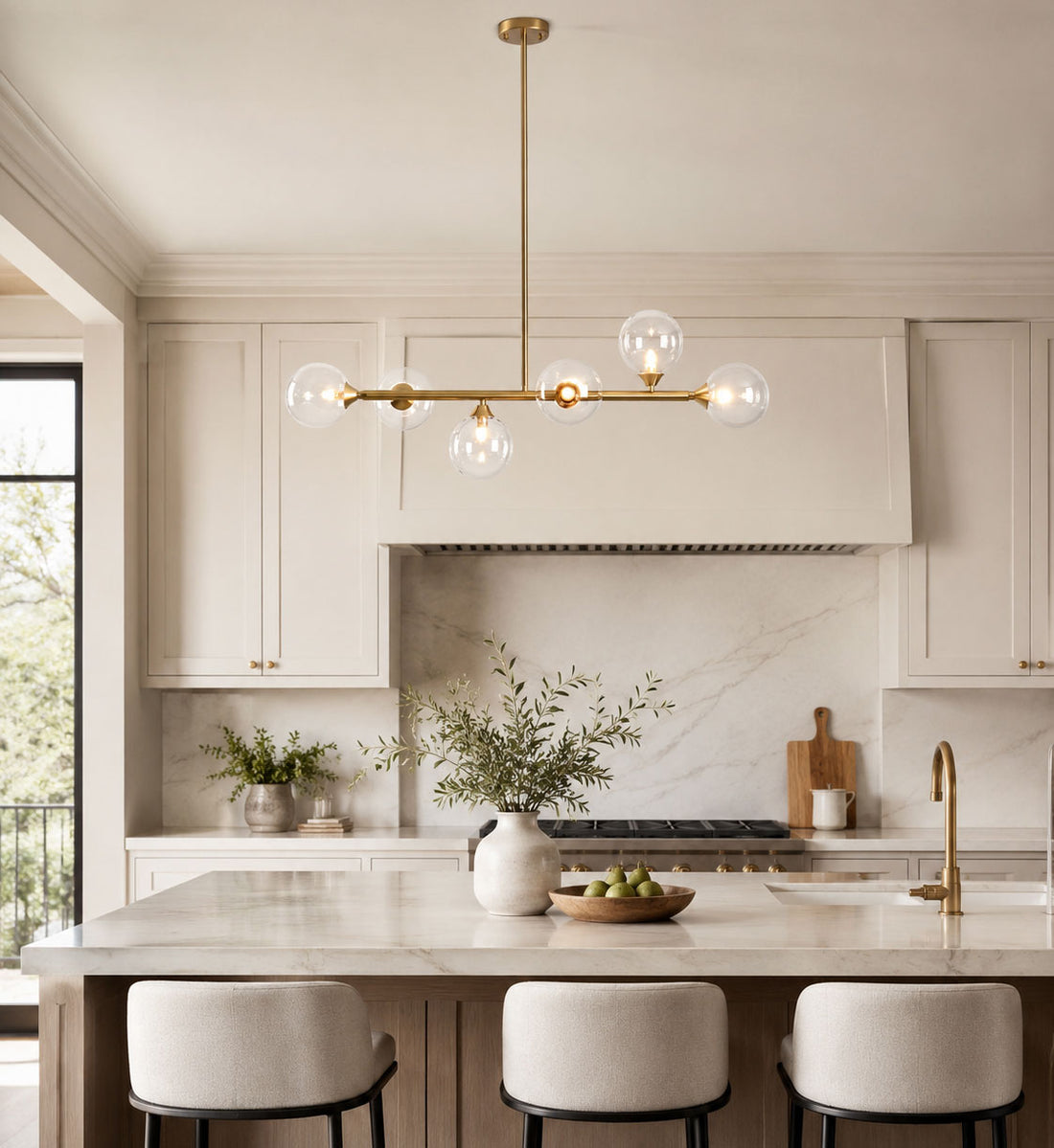 Calla gold linear glass globe pendant over a marble kitchen island in daylight