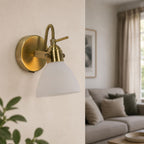 Callas antique brass wall spot light with opal glass shade lit in a living room