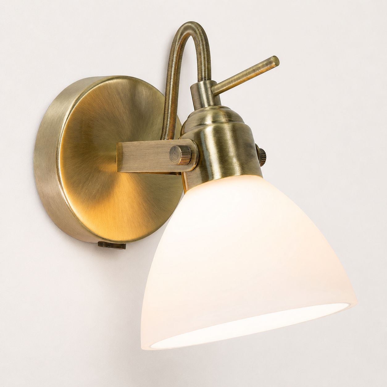 Callas antique brass switched wall spot light with opal glass shade, on white
