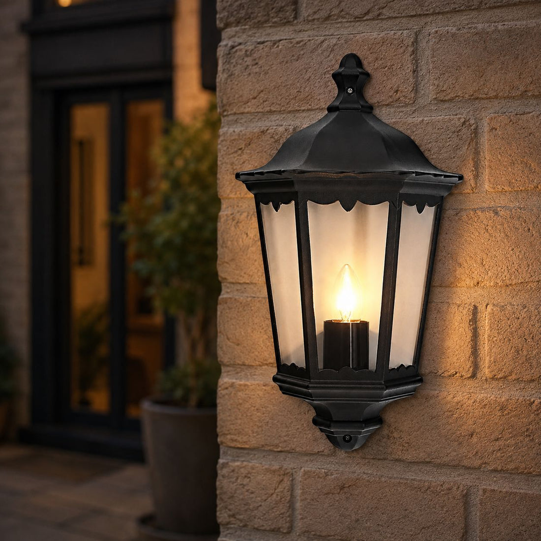 Corben matt black half lantern lit on a brick wall next to a front door