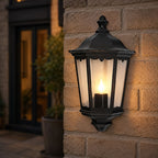 Corben matt black half lantern lit on a brick wall next to a front door