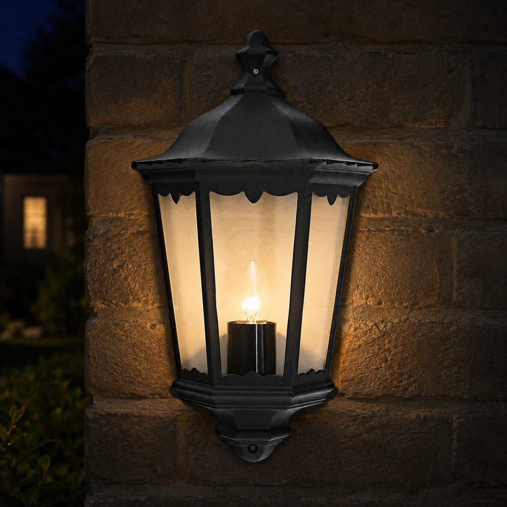 Corben black half lantern lit on a brick wall at dusk