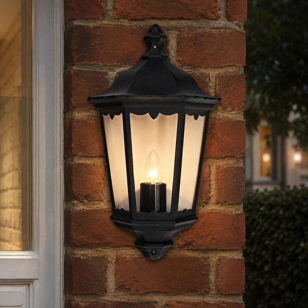 Corben black half lantern wall light lit on a red brick wall beside a window