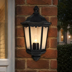 Corben black half lantern wall light lit on a red brick wall beside a window