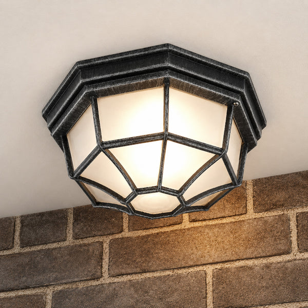 Corvus caged ceiling lantern lit against rustic stone at night