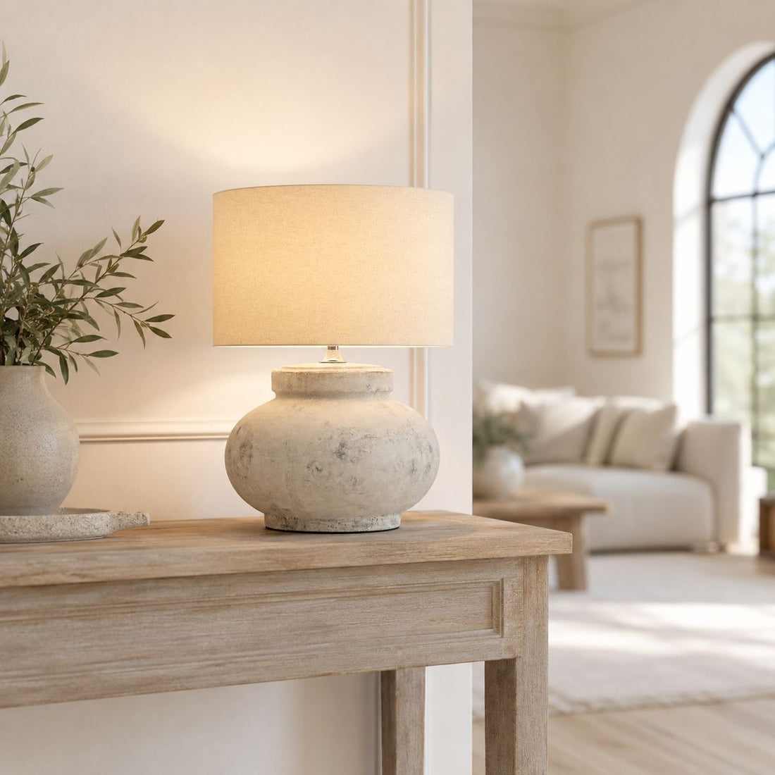 Darcy squat table lamp on a console table in a living room with arched window
