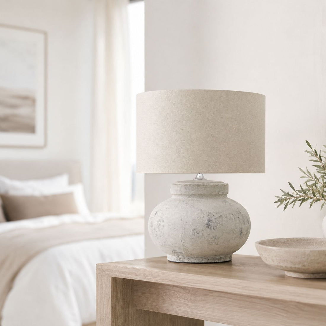 Darcy squat antique white table lamp on a bedside table in a bright bedroom
