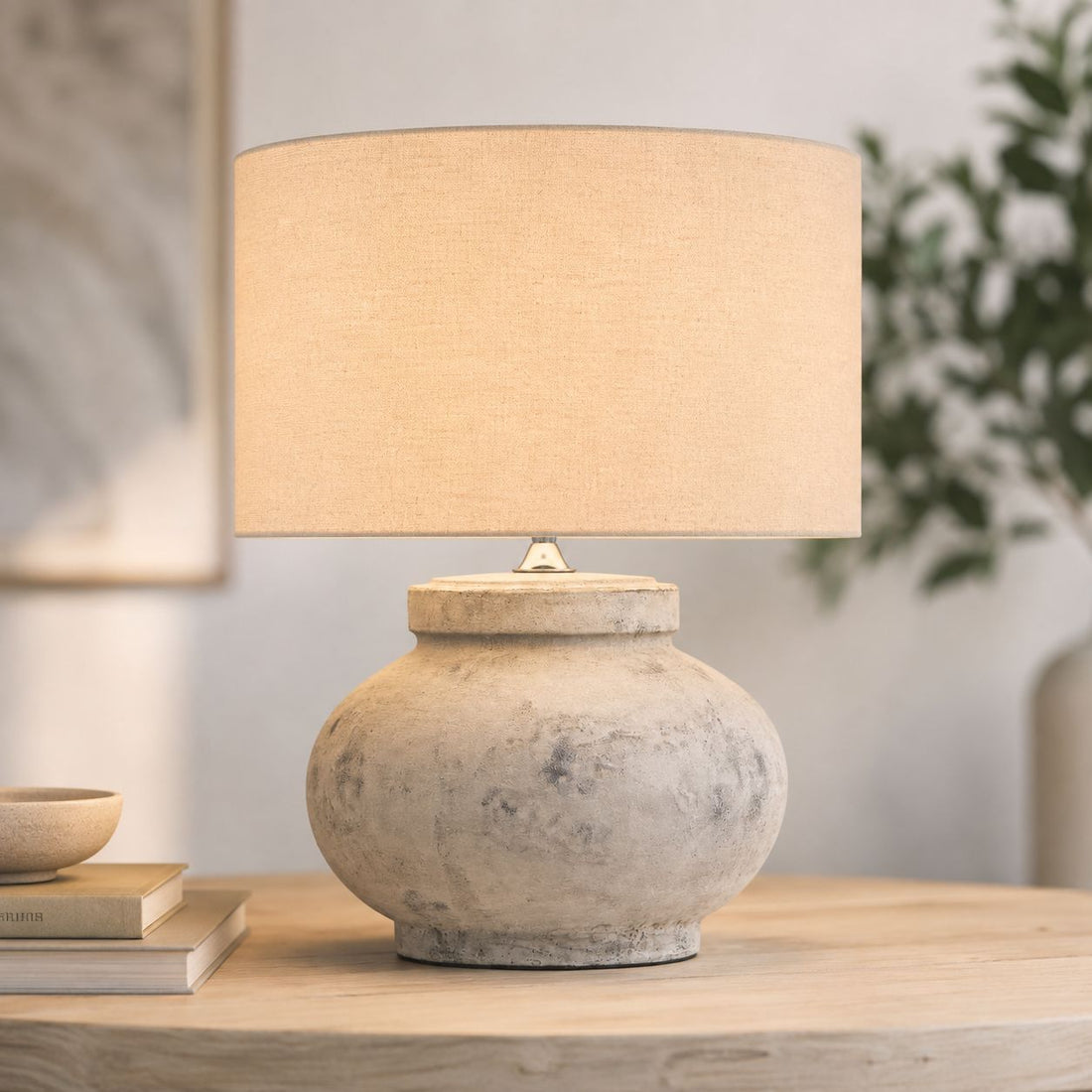 Darcy squat white stone-effect lamp lit on a side table by a window