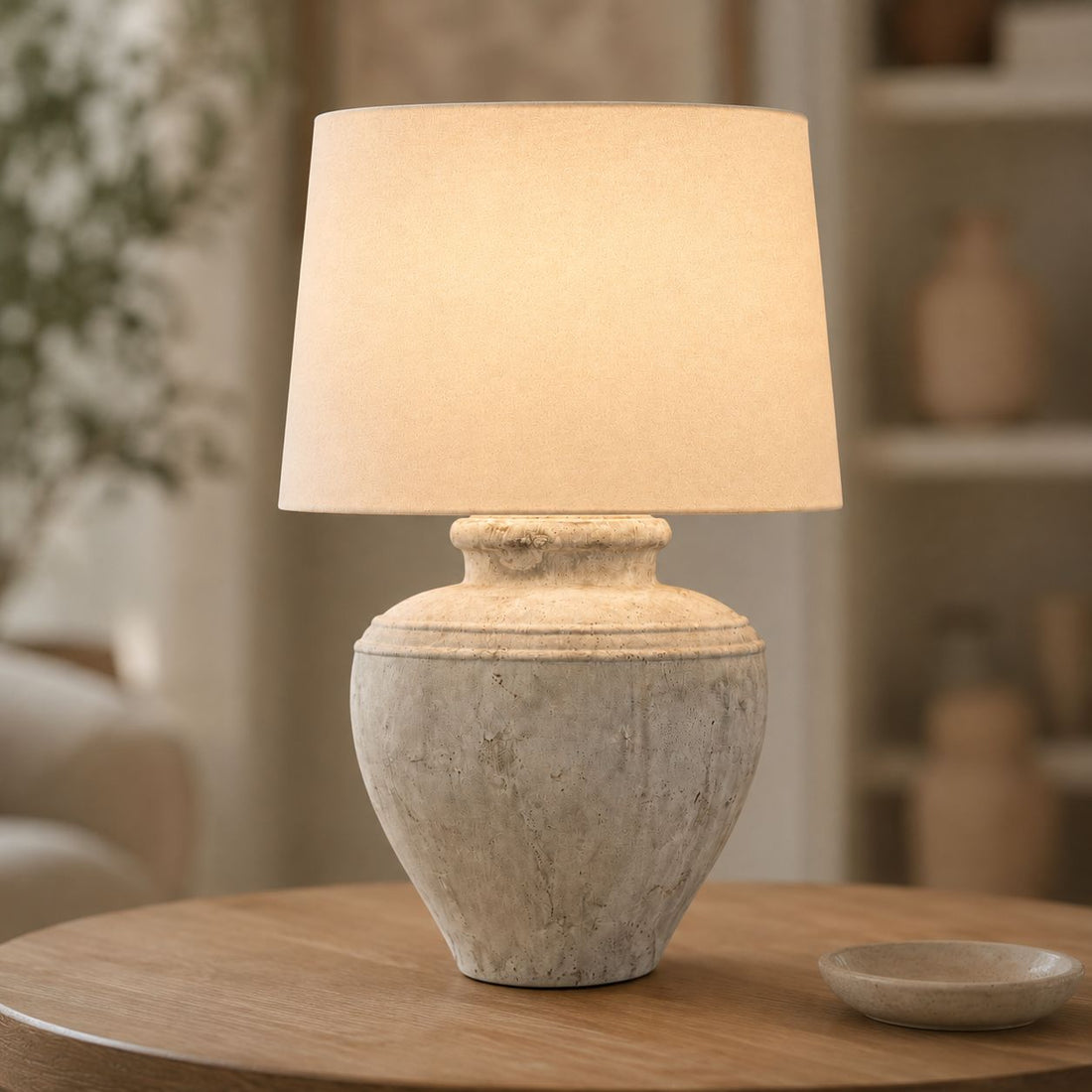 Darcy Chorus antique white stone table lamp with linen shade lit on a side table