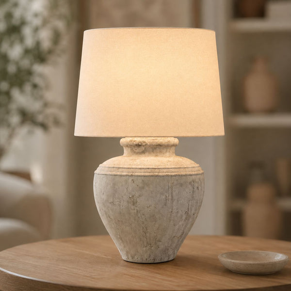 Darcy Chorus antique white stone table lamp with linen shade lit on a side table