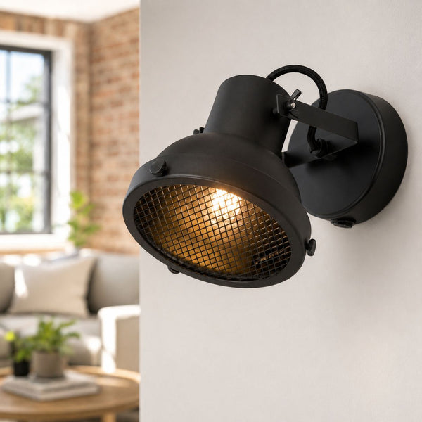 Forge matt black caged wall spot light lit in a living room with brick wall