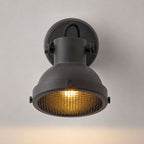 Forge matt black switched wall spotlight with mesh cage, front view on white