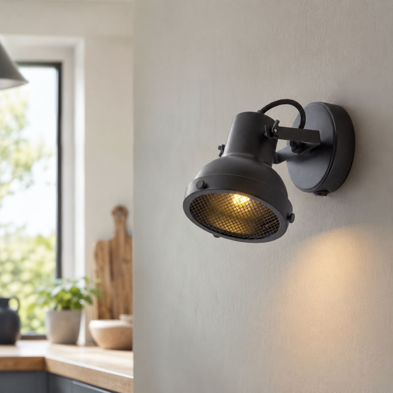 Forge matt black wall spot light lit in a kitchen beside a window