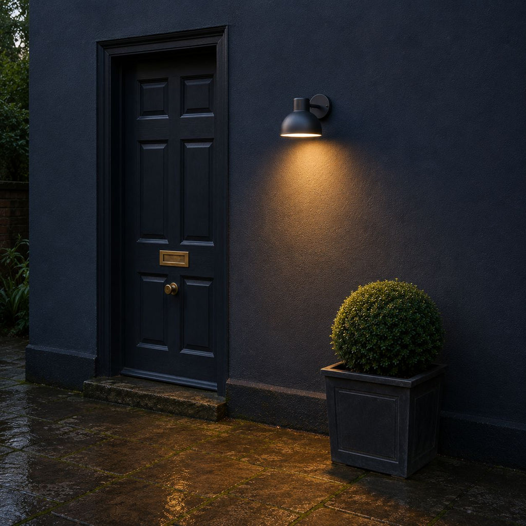 Hadsten matt black down light lit next to a navy front door at dusk
