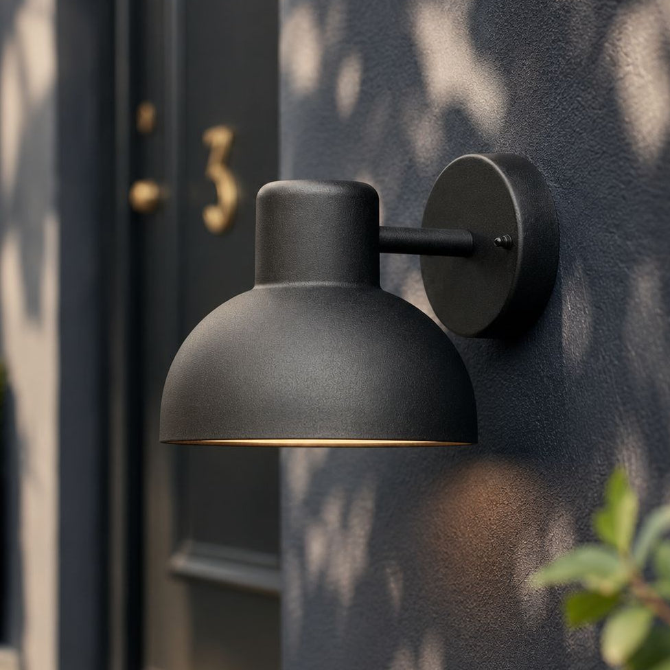 Hadsten matt black dome outdoor wall light lit on a navy wall