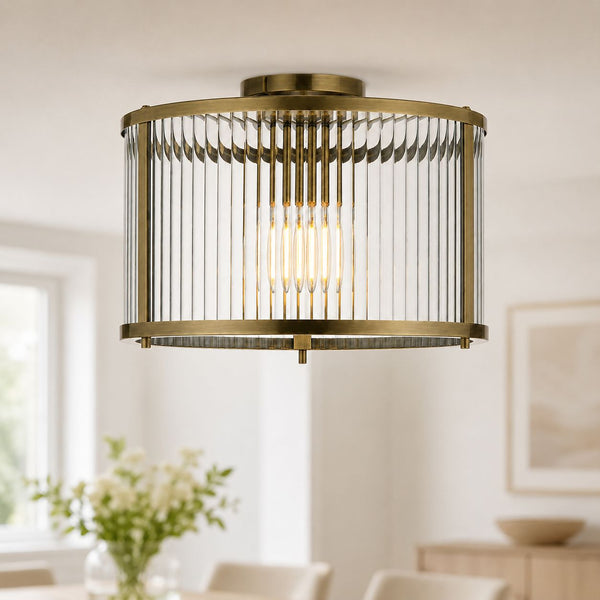 Halo antique brass flush ceiling light with clear ribbed glass, lit in a living room