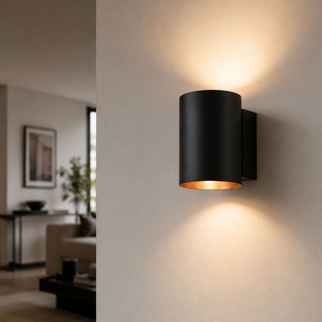 Jen black and gold cylinder wall light lit in a living room