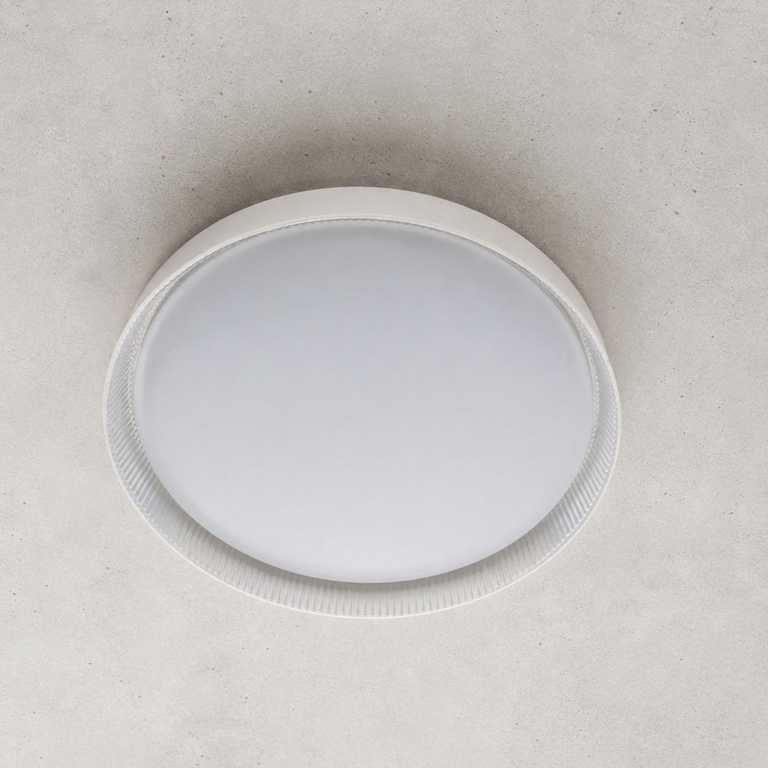 Kaos 40cm round LED light flush on a concrete ceiling, lit