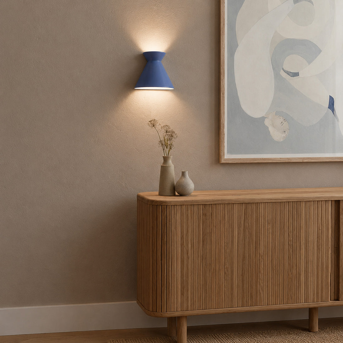 Kiro Provence blue sconce lit over a tambour sideboard with dried flowers