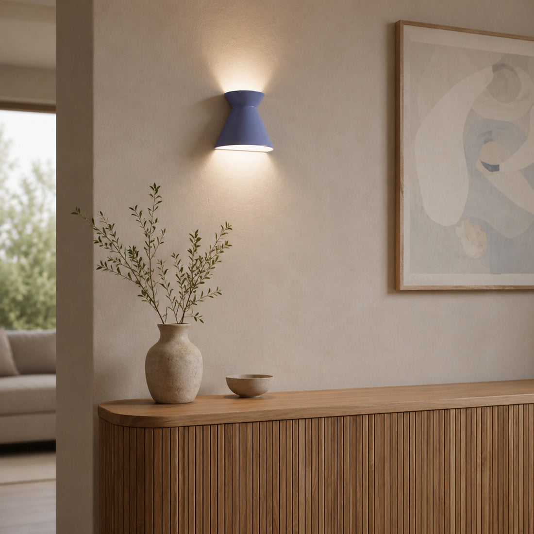 Kiro small blue wall light glowing above foliage on a curved oak console