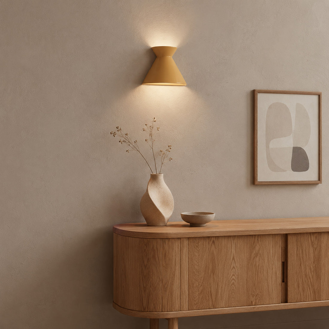 Small Kiro yellow sconce lit above a sculptural vase on an oak sideboard