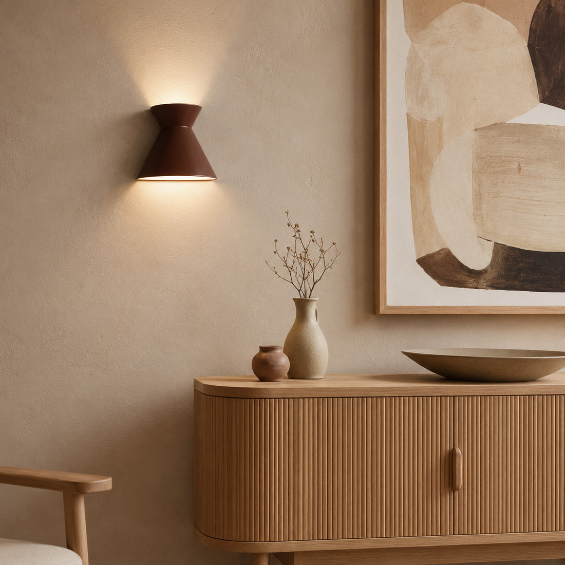 Kiro cocoa sconce glowing over a curved tambour unit with vases