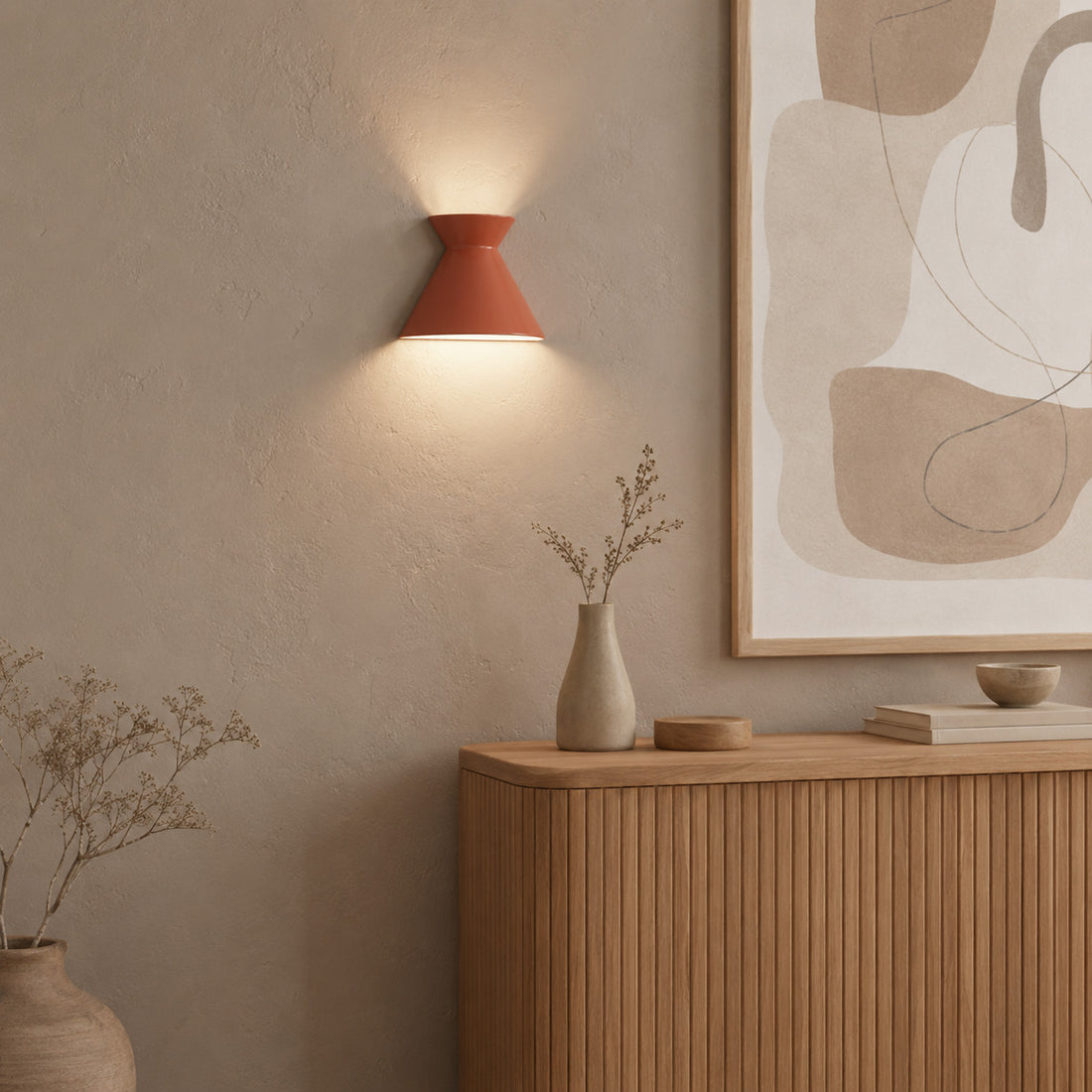 Kiro terracotta sconce glowing over a fluted console with dried stems