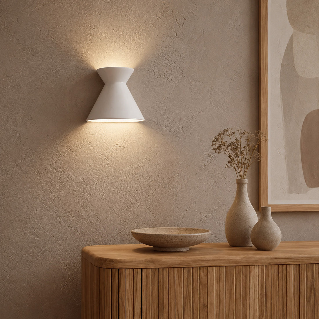 Small Kiro pure white sconce glowing on textured plaster above ceramics