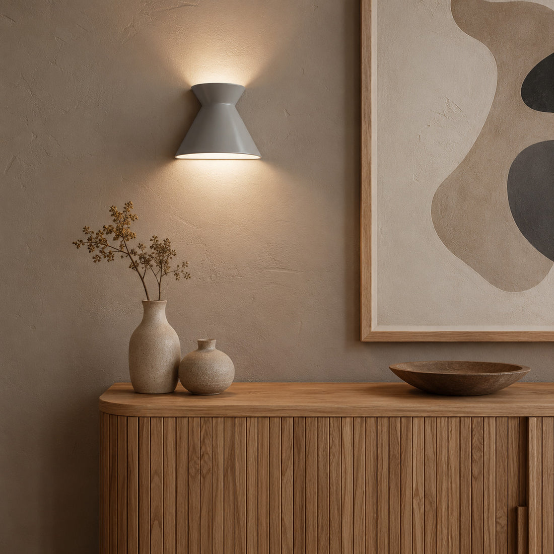 Kiro small grey wall light glowing over vases on an oak sideboard