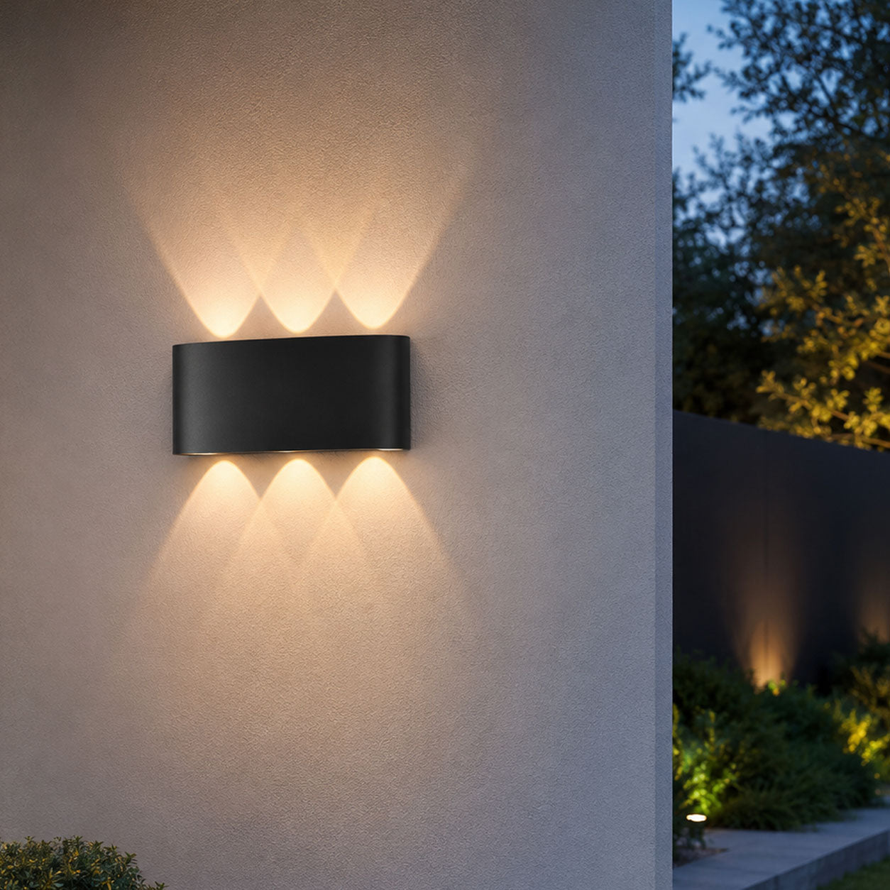 Kyra anthracite up down wall light casting light beams on a white wall at dusk