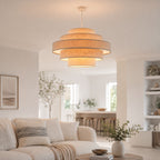 Linna oatmeal tiered pendant lit above a living room with cream sofa