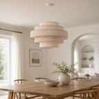 Linna oatmeal tiered linen pendant lit above a dining table in a bright room