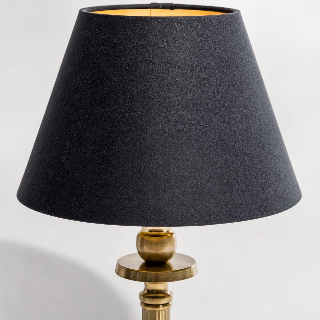 Lira table lamp, close-up of the black shade with gold lining and brass stem