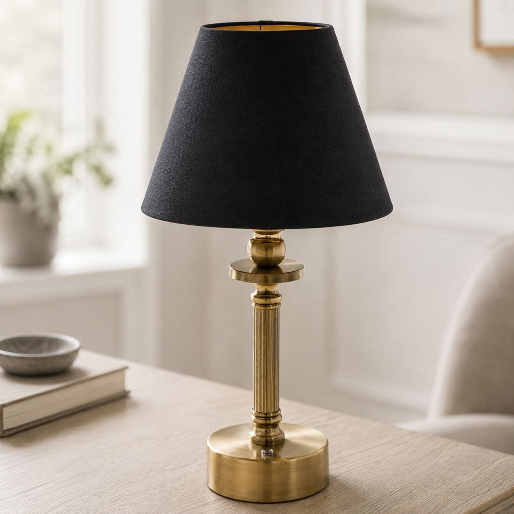 Lira cordless brass table lamp with black shade on a coffee table in a living room