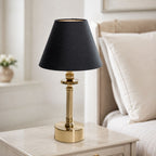 Lira brass rechargeable table lamp with black shade on a marble side table