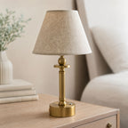 Lira brass rechargeable table lamp with oatmeal shade on a wooden bedside table