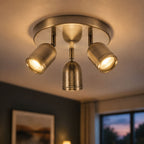 Lucca antique brass triple spot ceiling light lit in a living room at dusk