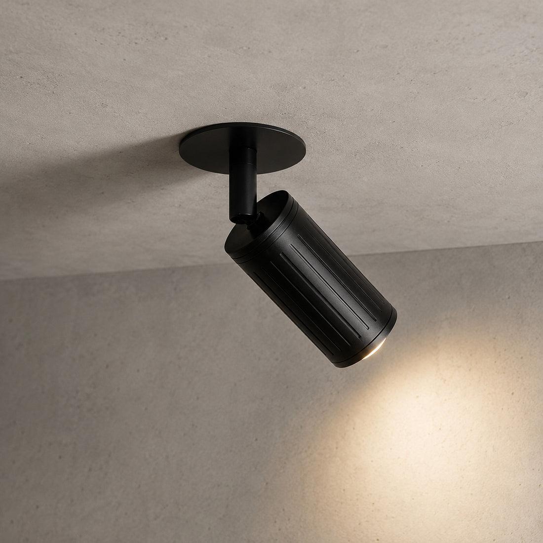 Angled Luminar black ceiling spotlight casting a warm pool of light