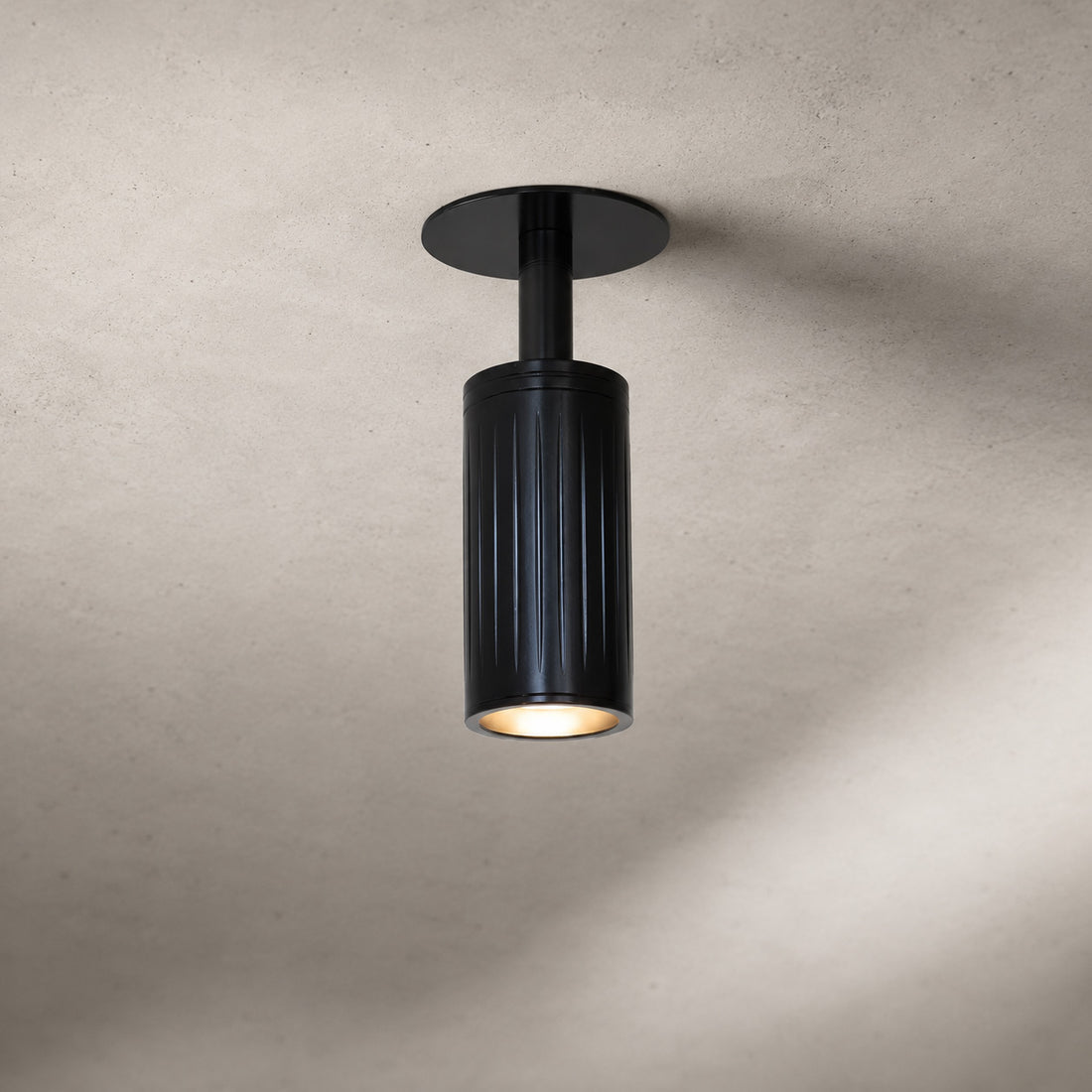 Luminar black ribbed ceiling spot pointing straight down, lit