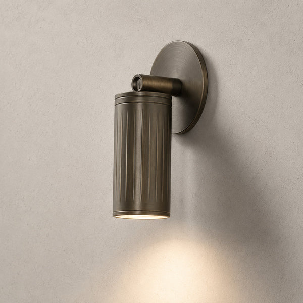Luminar browned brass adjustable wall spotlight angled down, lit