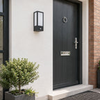 Lyon black PIR outdoor wall light on a white wall next to a grey door in daylight