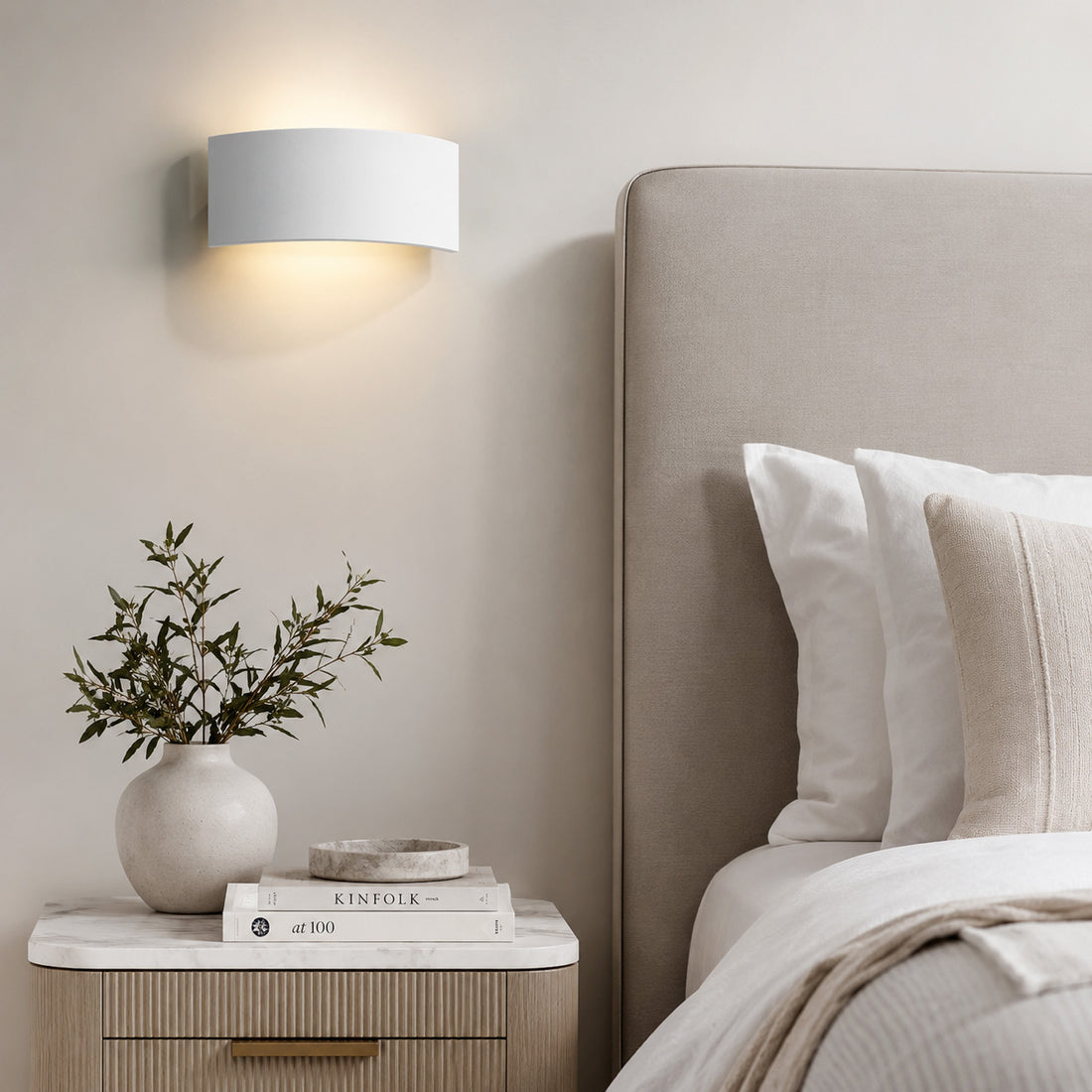Mood plaster wall light glowing above a marble-topped bedside table