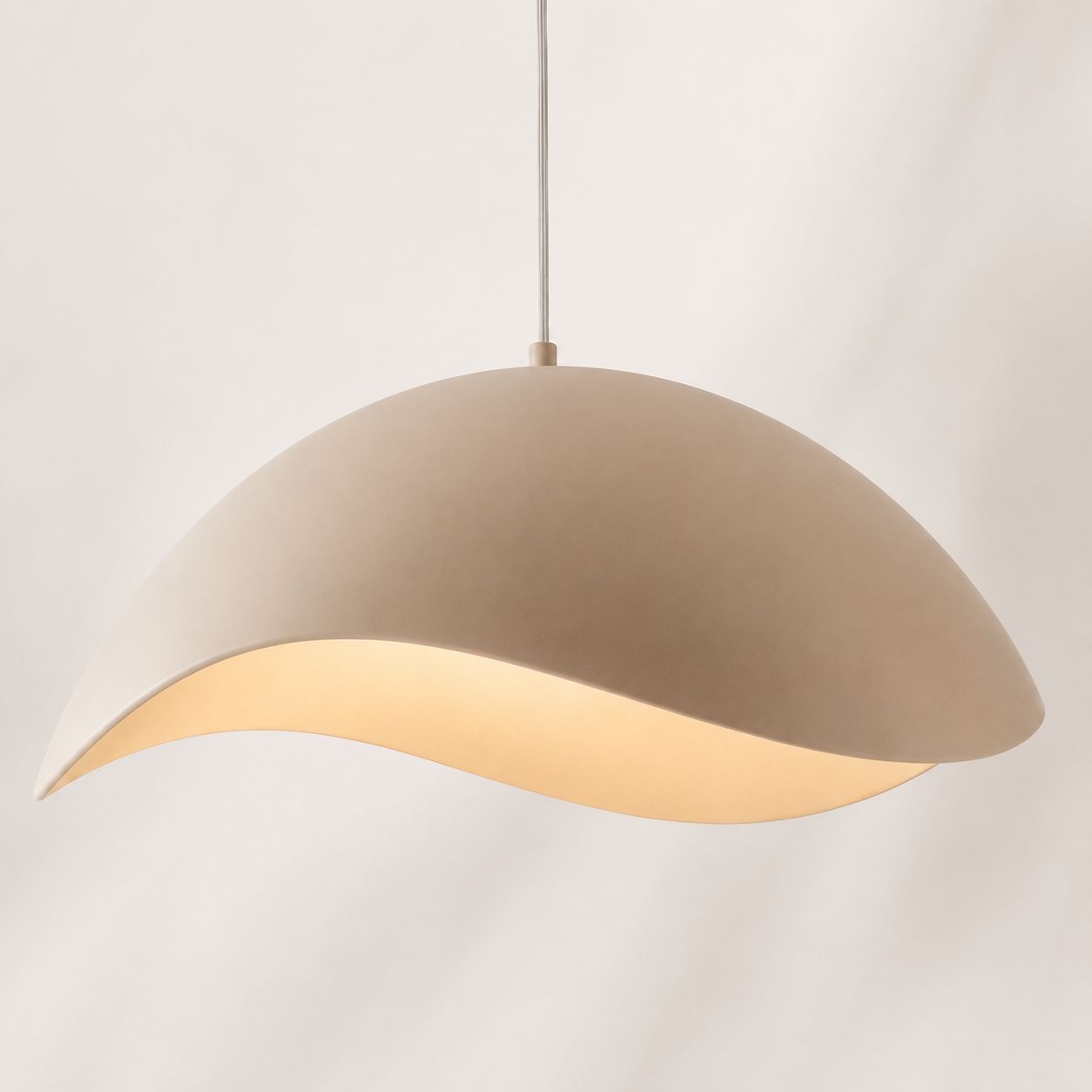 Nami sand taupe wavy metal pendant with warm glow beneath, angled view on white